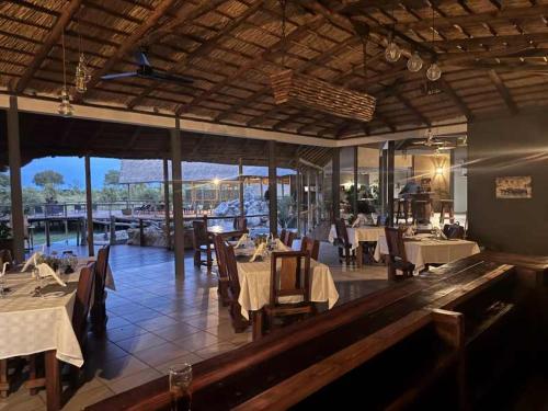 a restaurant with tables and chairs with a view of the water at Mababe River Campsite in Mababe