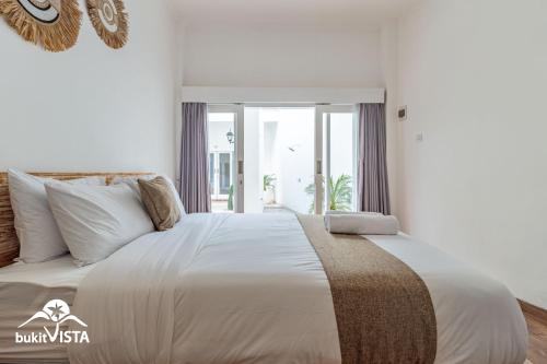 a bedroom with a large white bed with a window at Mo Cactus by Bukit Vista in Tumbak Bayuh