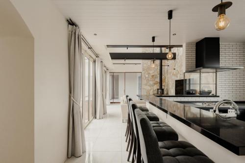 a kitchen with a long counter with black chairs at Play Stay 一宮 サウナ BBQ 広々ガーデン in Ichinomiya