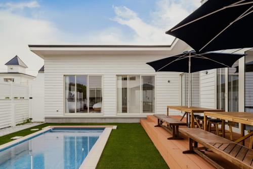 a patio with a table and benches and a pool at Play Stay 一宮 サウナ BBQ 広々ガーデン in Ichinomiya