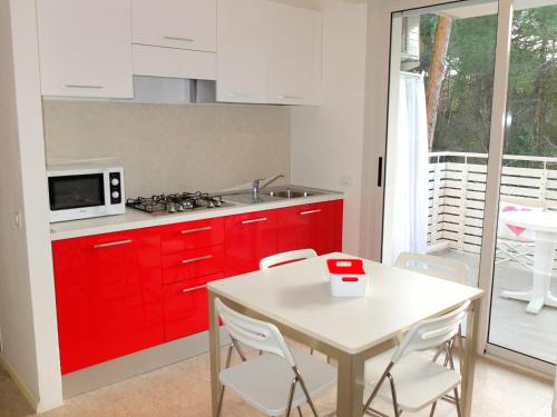 リニャーノ・サッビアドーロにあるResidence Valgardenaのキッチン(赤いキャビネット、テーブル、椅子付)