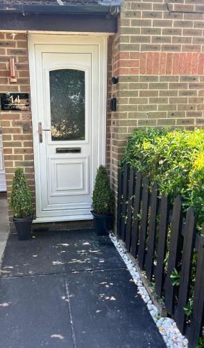 a white door on a brick house with two plants at Niamh's Place in Northallerton