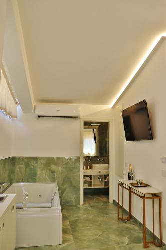 a living room with a couch and a tv on the wall at Scilla Luxury Rooms in Scilla