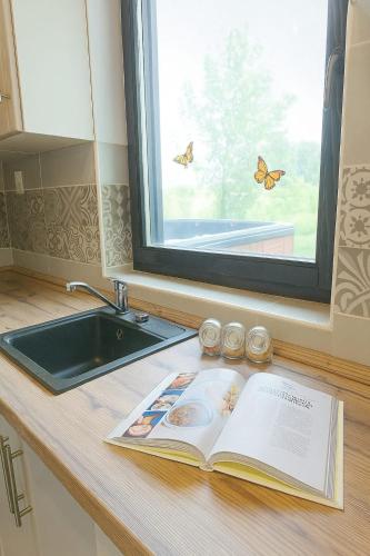a book on a kitchen counter with a window and butterflies at Nowhere Villa in Nyírmihálydi