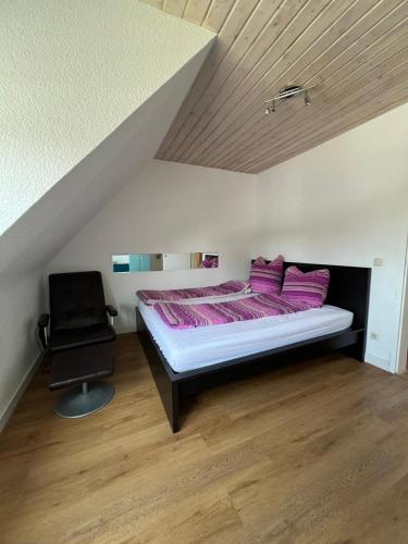 a bedroom with a bed with purple pillows and a chair at Gemütliche Ferienwohnung in Essen