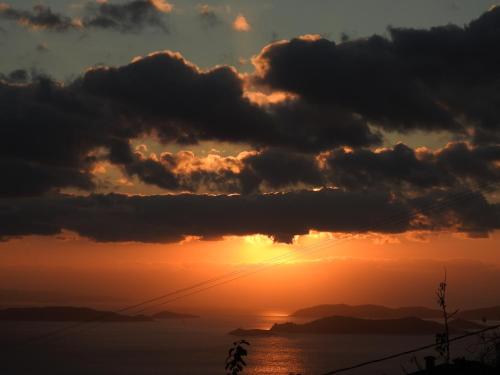 a sunset over the ocean with clouds at Dimitra's house in Glóssa