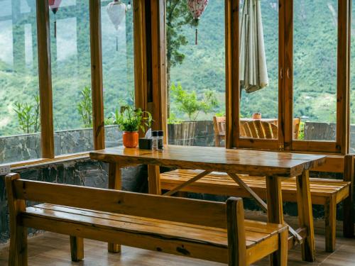 a wooden table and bench in a room with windows at Muong Hoa Eco Villa in Sa Pa