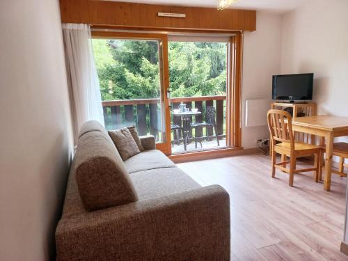 un salon avec un canapé, une table et une fenêtre dans l'établissement Sur le T M B centre village studio lumineux, aux Contamines-Montjoie