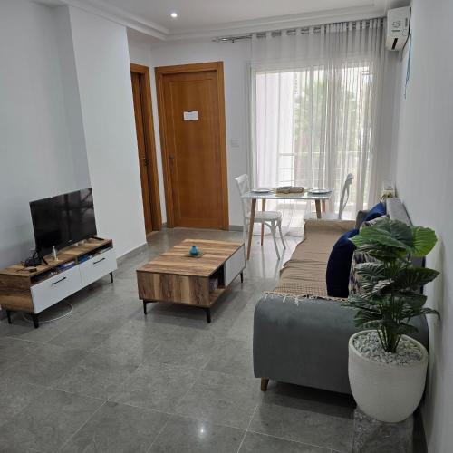 a living room with a couch and a tv and a table at Pépite au cœur du Belvédère Tunis in Bāb as Suwayqah