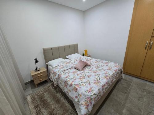a bedroom with a bed with a floral bedspread at Pépite au cœur du Belvédère Tunis in Bāb as Suwayqah