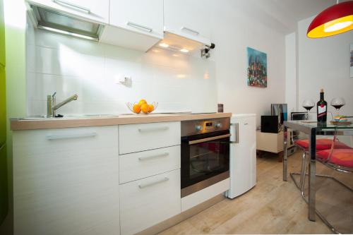 uma cozinha com armários brancos, um lavatório e uma mesa em Ayre Apartman Split em Split