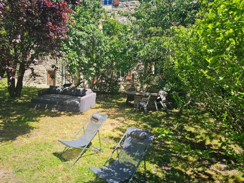 two lawn chairs and a couch in a yard at Moulin au Bord de l'Eau Calme et Nature in Saint-Léger-de-Peyre