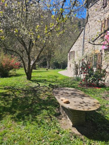 a stone bench sitting in the grass next to a building at Moulin au Bord de l'Eau Calme et Nature in Saint-Léger-de-Peyre