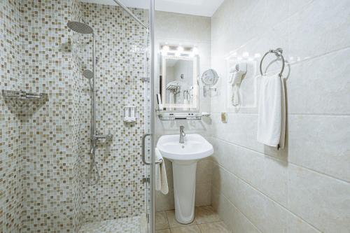 a white bathroom with a sink and a shower at Daniel Hill Hotel in Tashkent