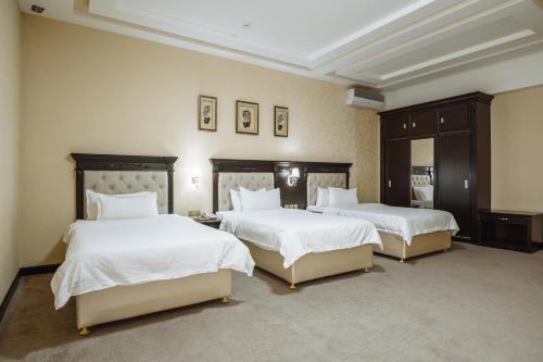 a bedroom with two beds with white sheets at Daniel Hill Hotel in Tashkent