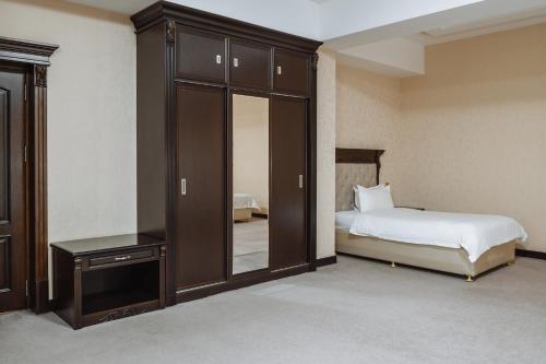 a bedroom with a bed and a cabinet with a mirror at Daniel Hill Hotel in Tashkent
