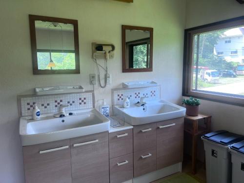 a bathroom with two sinks and two mirrors at Itadaki Chalet in Myoko