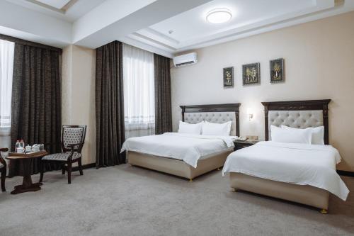 a hotel room with two beds and a chair at Daniel Hill Hotel in Tashkent