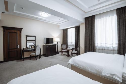 a hotel room with two beds and a desk at Daniel Hill Hotel in Tashkent