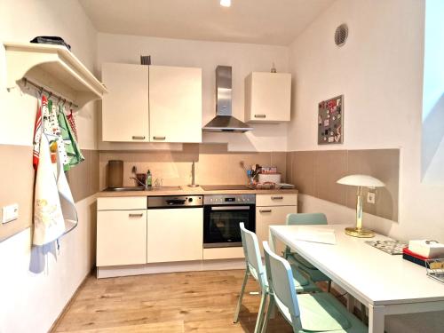 a kitchen with white cabinets and a table and chairs at CALM & GREEN by JR City Apartments in Vienna