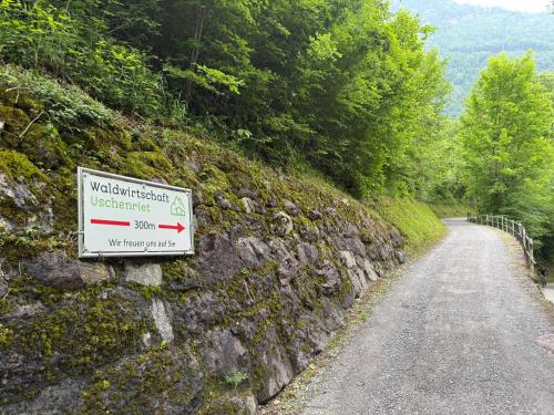 a sign on a stone wall next to a road at Mitten in den Glarner Alpen Hot Tub & Alpenblick in Ennenda