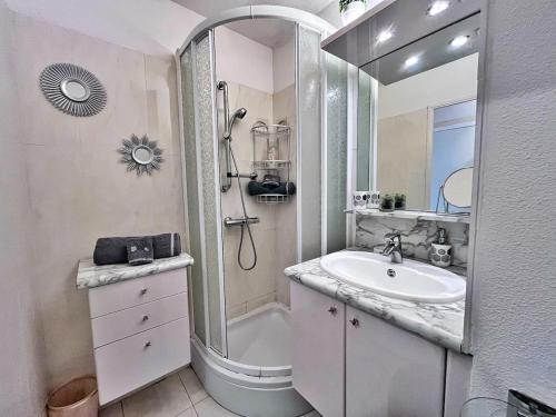 une salle de bain blanche avec un lavabo et une douche dans l'établissement Rez de jardin privatif à 150m de la mer, à Villefranche-sur-Mer