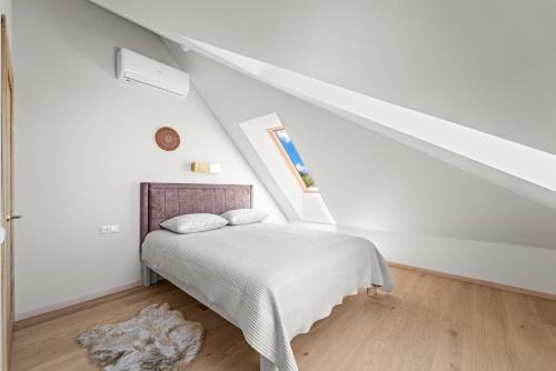 a white bedroom with a bed in a attic at Dunique in Palanga