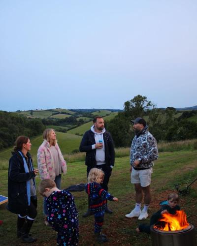 a group of people standing around a fire at Hidden Valley Dorset in Powerstock