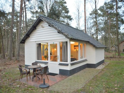 a small white cottage with a table and chairs at Completely detached bungalow in a nature-filled park by a large fen in Stramproy