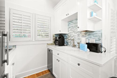a white kitchen with white cabinets and a microwave at Spice in Santa Rosa Beach