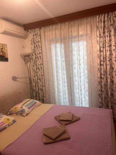 a bed with two towels on it with a window at Una apartmani Petrovac in Petrovac na Moru