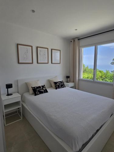 une chambre blanche avec un grand lit et une fenêtre dans l'établissement Villa vue mer neuve 3754, aux Issambres