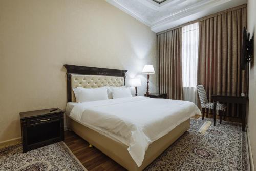 a bedroom with a large white bed and a desk at Daniel Hill Hotel in Tashkent