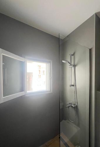 a bathroom with a shower and a window at Douskos Guesthouse in Hydra