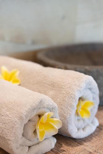 two rolled towels with yellow flowers on a table at Jepun Didulu Cottages in Candidasa