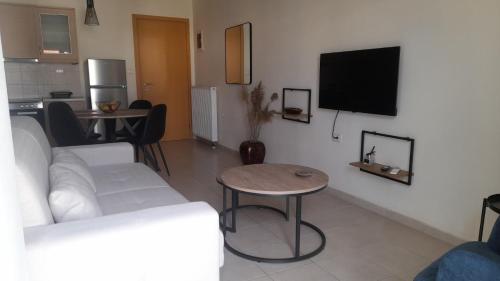 a living room with a couch and a tv on a wall at Ifigeneia Infinity Suites in Néa Alikarnassós