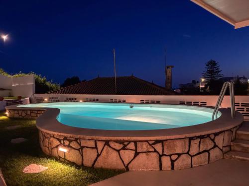 a large swimming pool in a yard at night at House T3 with Sea View and Private Pool - 5 minutes walk from the beach in Sesimbra