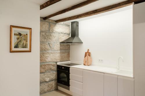 a kitchen with white cabinets and a stone wall at Belo Douro - Private Pool - Douro Valley - by RowdHouses in Paços de Gaiolo