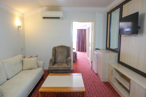 una sala de estar con un sofá y un televisor en AZAK BLUE OTEL, en Okurcalar