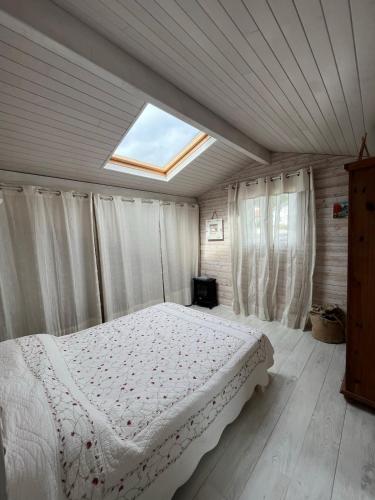 une chambre avec un lit blanc avec une lucarne dans l'établissement Villa avec piscine Anglet proche Biarritz, à BIQ