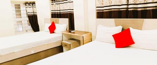 two beds with red pillows in a room at Hotel Raj DUNIYA GUEST House Kalighat WB With AC OR NON AC Room in Kolkata