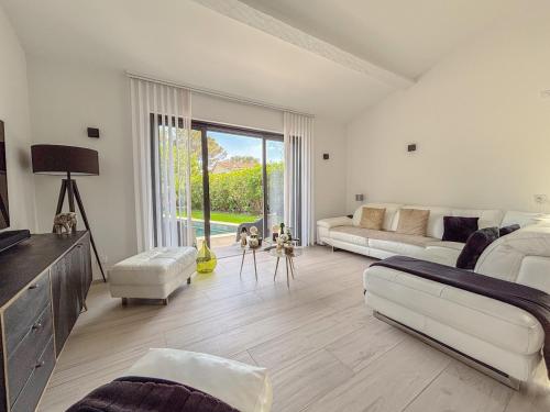 un salon avec des meubles blancs et une grande fenêtre dans l'établissement Villa contemporaine, 5 voyageurs avec piscine, jardin et proche du bord de mer, à Saint-Raphaël