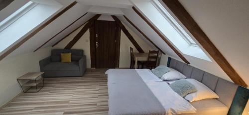 a attic bedroom with a bed and a chair at Syrenka Apartamenty in Ustka