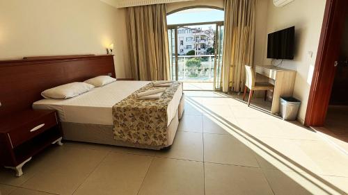 Una habitación de hotel con una cama y una ventana grande. en Forum Residence Hotel, en Marmaris