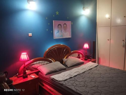 a bedroom with a bed with two lamps and a blue wall at John's House in Chalkida