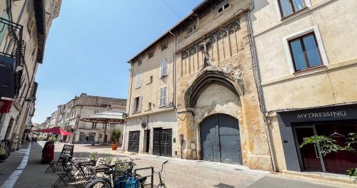 un vieux bâtiment dans une rue avec des tables et des chaises dans l'établissement AC - Hypercenter - Near place des Carmes, à Avignon