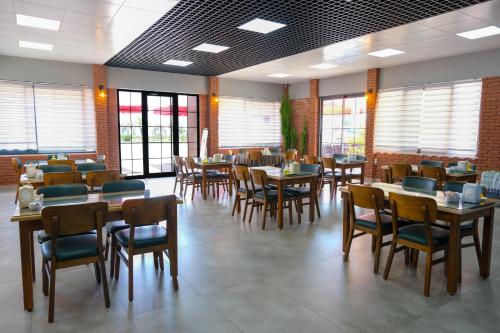 Un comedor con mesas y sillas y ventanas. en AZAK BLUE OTEL, en Okurcalar