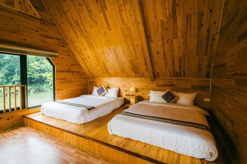 two beds in a room with wooden walls at Sapa Riverside Homestay in Sa Pa