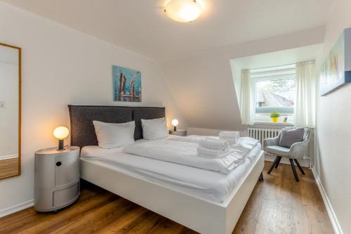 a bedroom with a large white bed and a chair at Haus Treibholz in Westerland