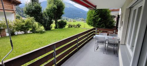 a balcony with chairs and a view of a green field at Gemütliches Appartement für Erholung und Sport in Klosters